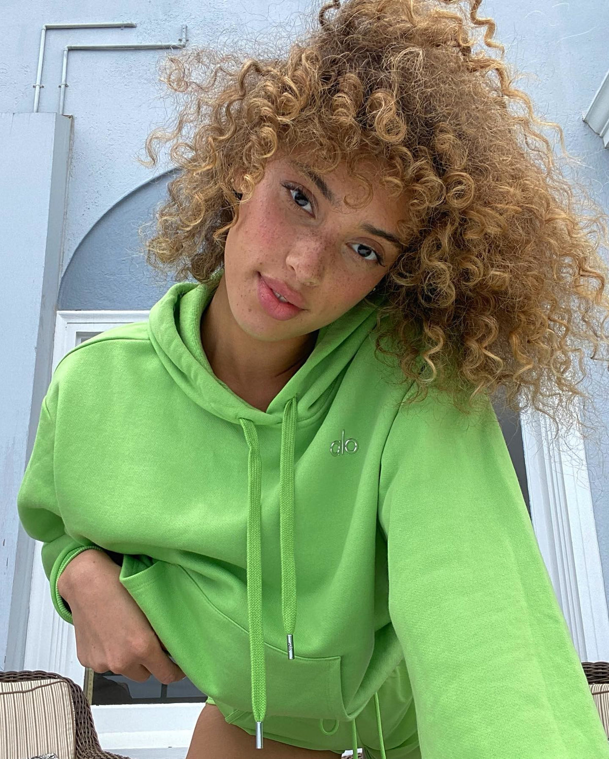 @khadijha wearing the Accolade Sweatshirt in Green Apple in a close up selfie.  